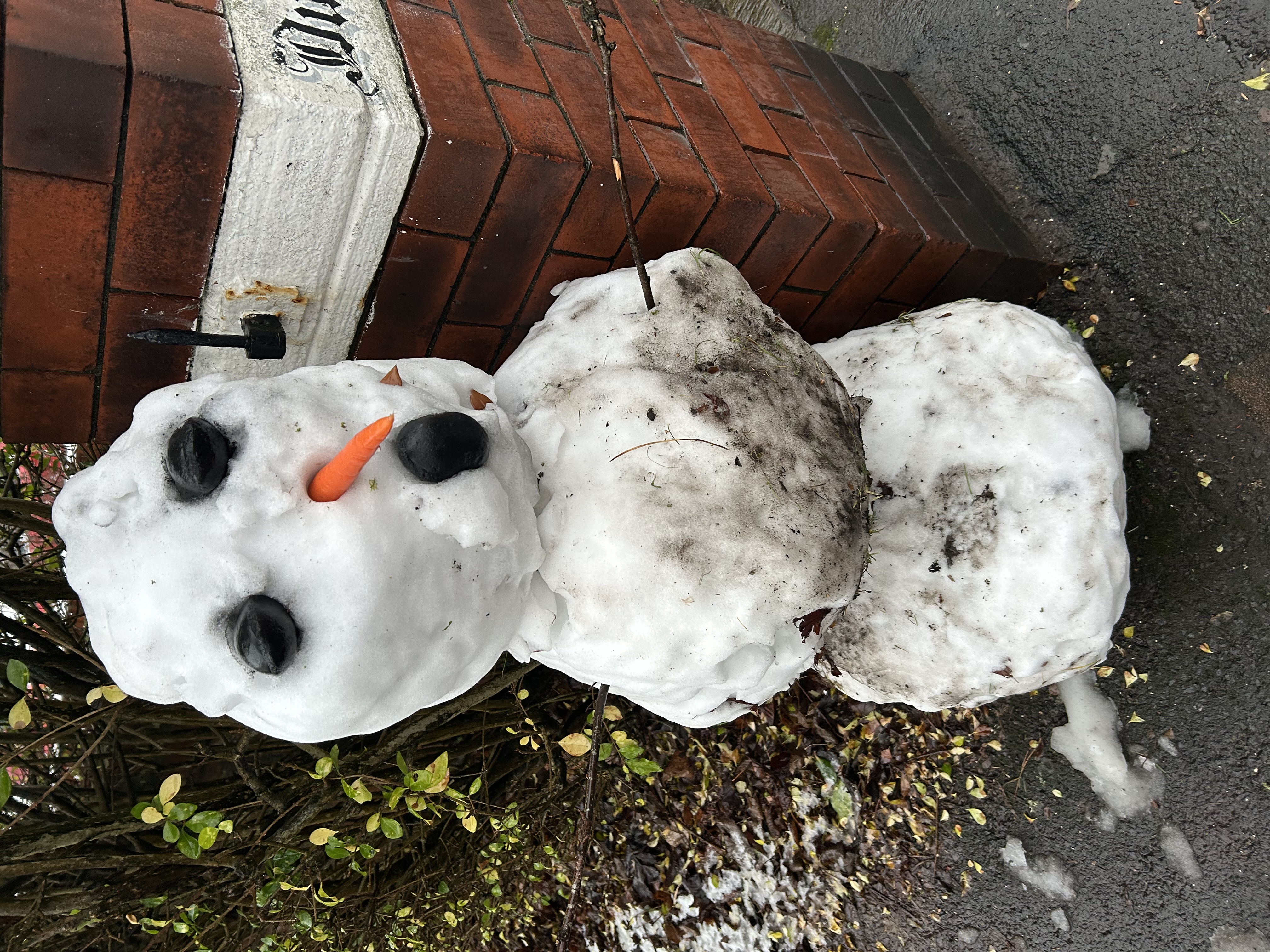 Photo of a snow person at the end of an 
		alleyway, the snow person is around 1.5m tall and has black objects for eyes and mouth; CC-BY-NC